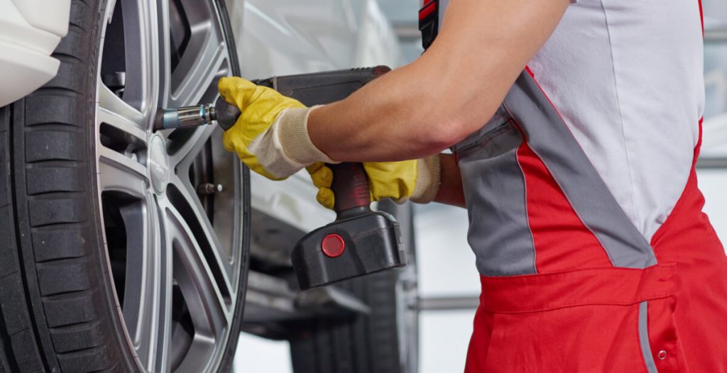 Auto mechanic removing wheel with cordless impact