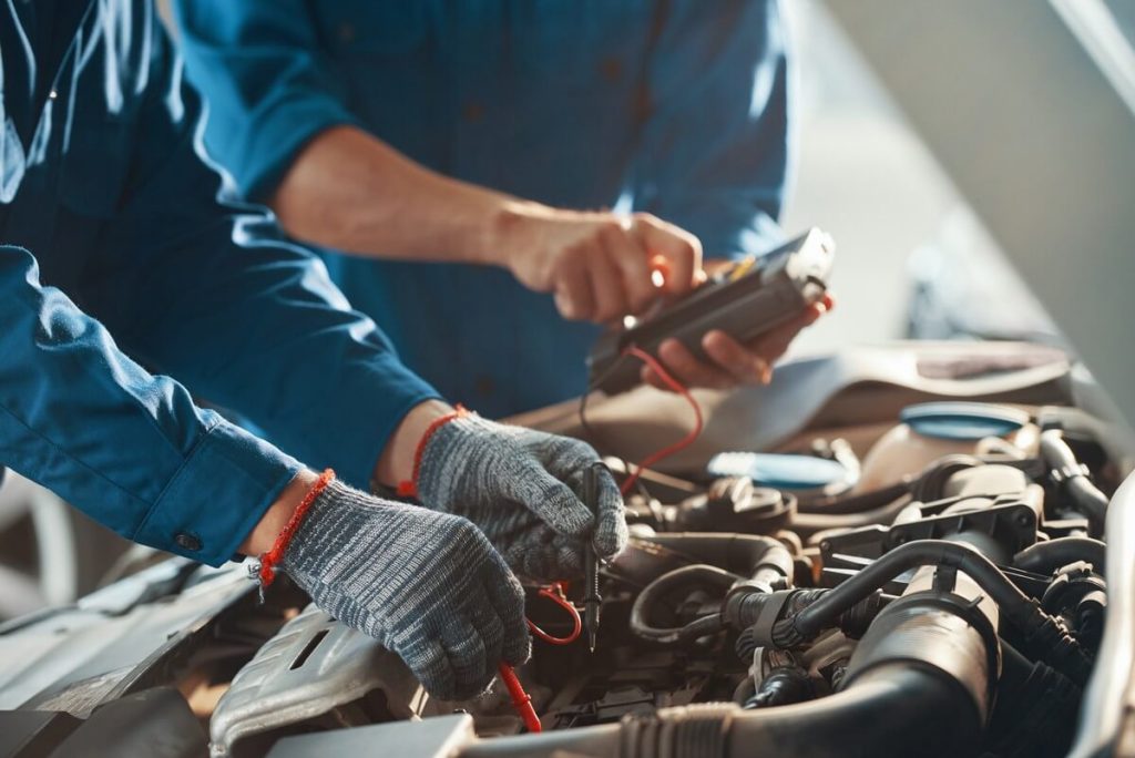 2 mechanics with automotive multimeter