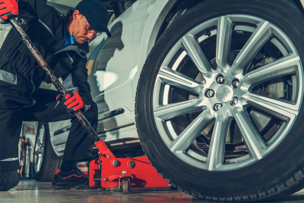 Auto mechanic using 3-ton floor jack