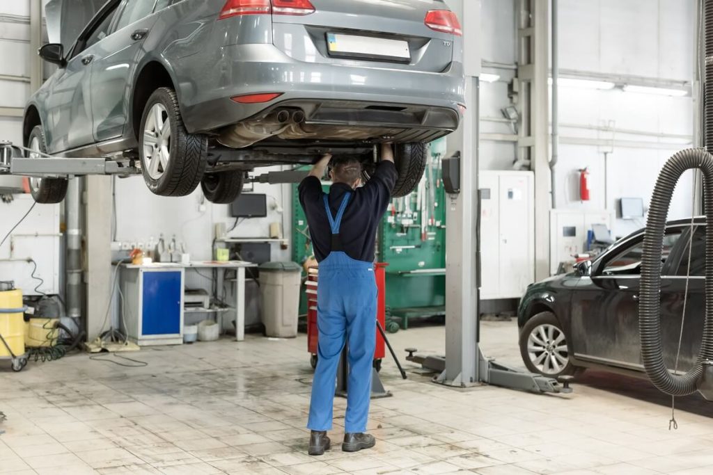 Mechanic working under 2-post car lift